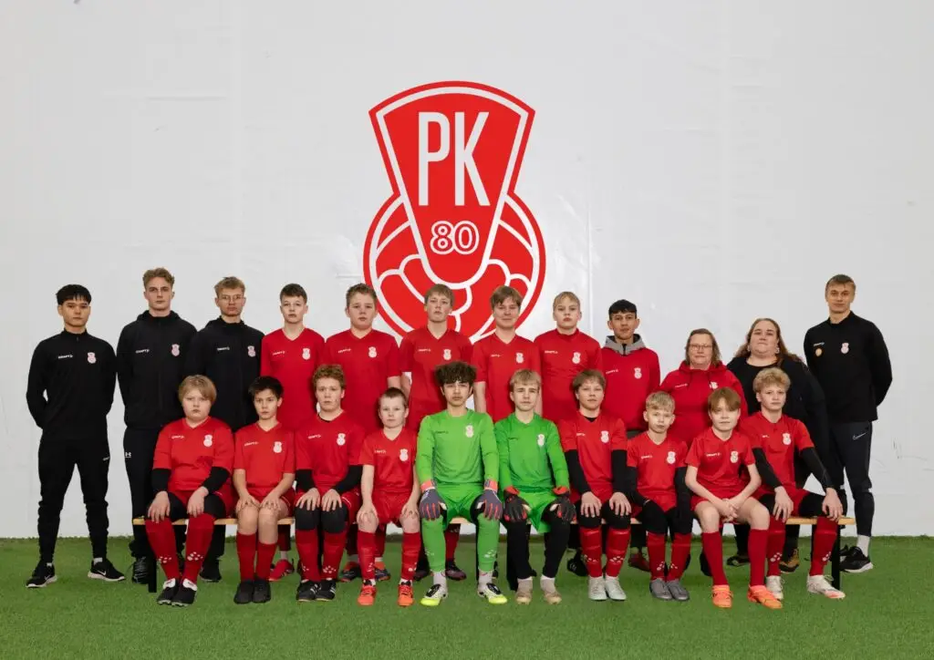 Mikkelin Pallo-Kissojen P14 juniorit iloisina joukkuekuvassa. Pelaajilla on joukkueen punainen peliasu.